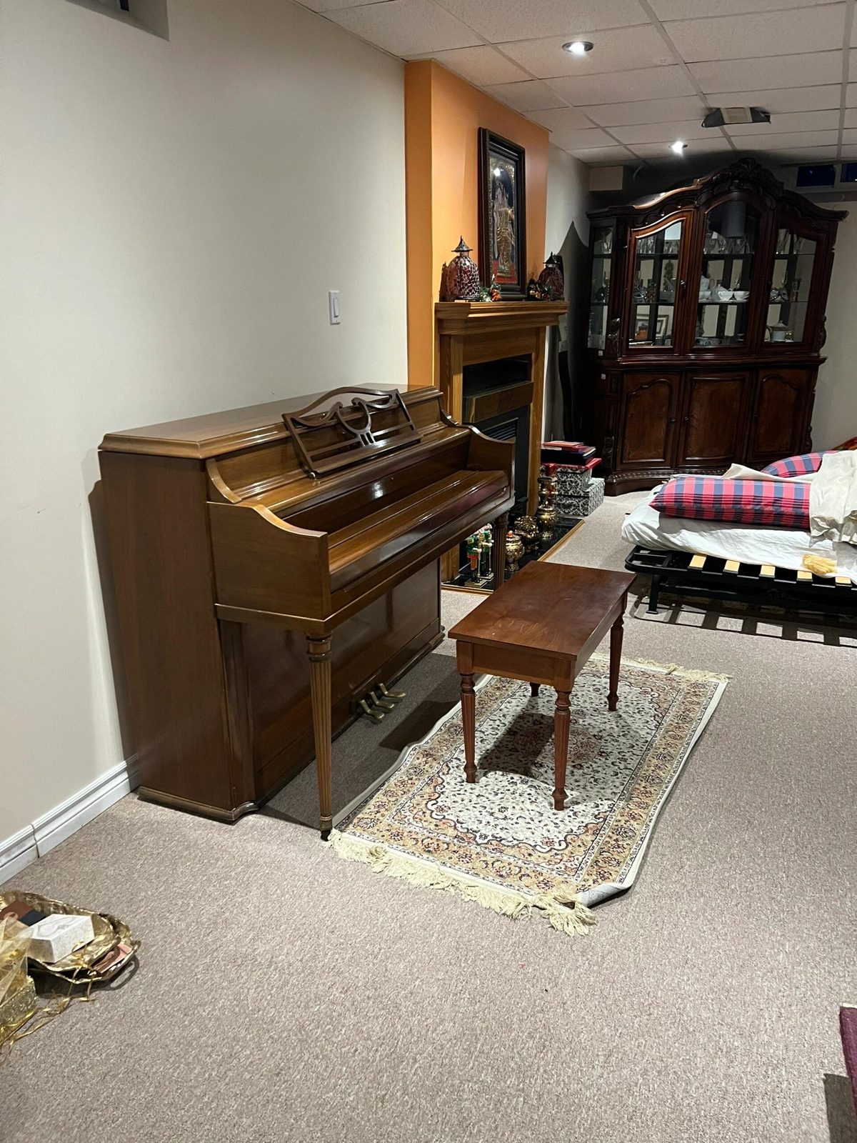 Upright piano standing in a finished basement before a Toronto piano move